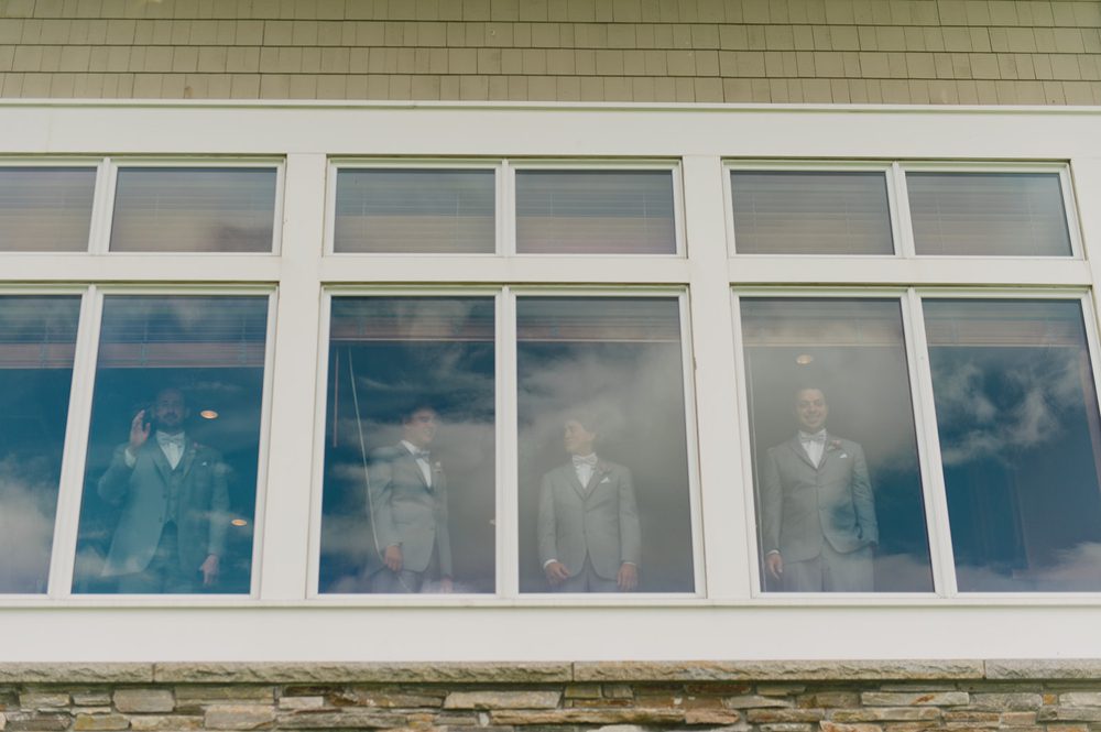 groomsmen-watching-first-look-through-window